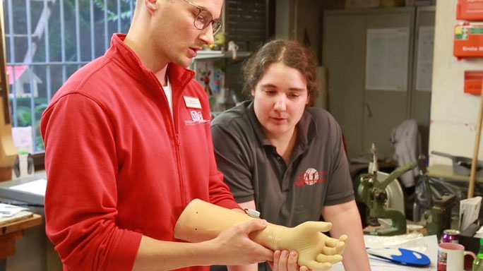 Zwei Orthopädietechnik-Mechaniker überprüfen in der Werkstatt eine elektrische Handprothese.